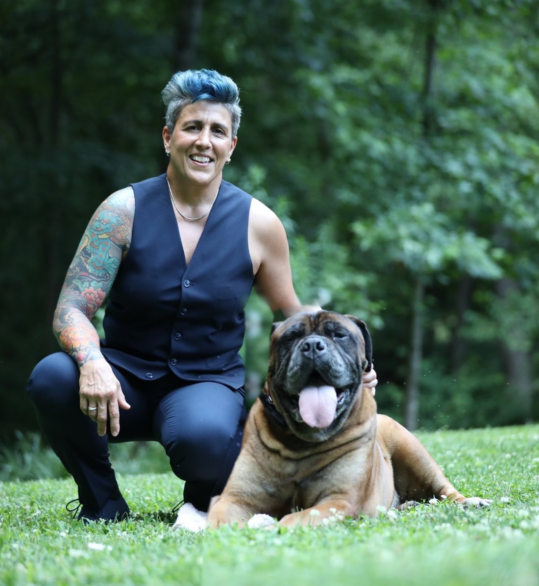 Lisa Long kneeling on the lawn beside her Bullmastiff